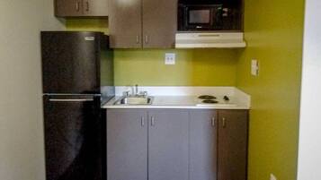 A compact kitchen with a refrigerator, sink, and microwave.