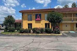 Un motel con fachada amarilla, techo rojo y un letrero que indica que es un motel y estudios número 6.