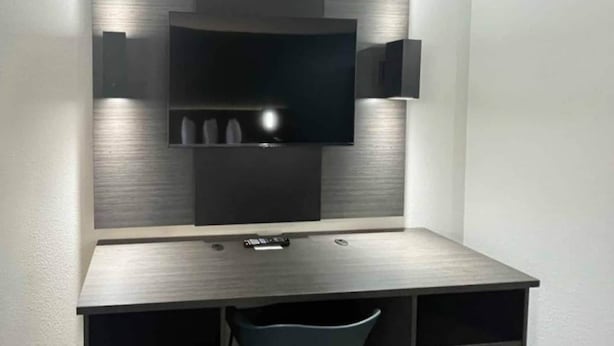 A modern, minimalist desk with a flat-screen TV mounted above it. - Comfy King Bed|Pool,Free Wifi&TV (Huntsville AL)