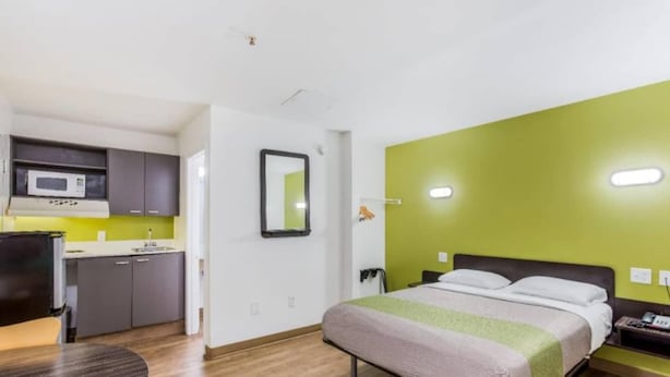 A compact hotel room with a bed, bedside table, and a kitchenette area. - Cozy King Bed|Free Wifi&Parking,TV (Jacksonville)