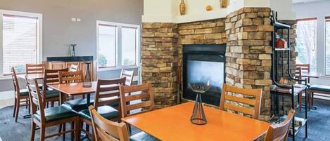A dining area with a stone fireplace, wooden chairs, and a table.