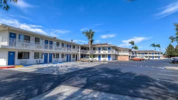 Un motel doté de nombreuses chambres, d’un parking et surplombant un ciel bleu dégagé.