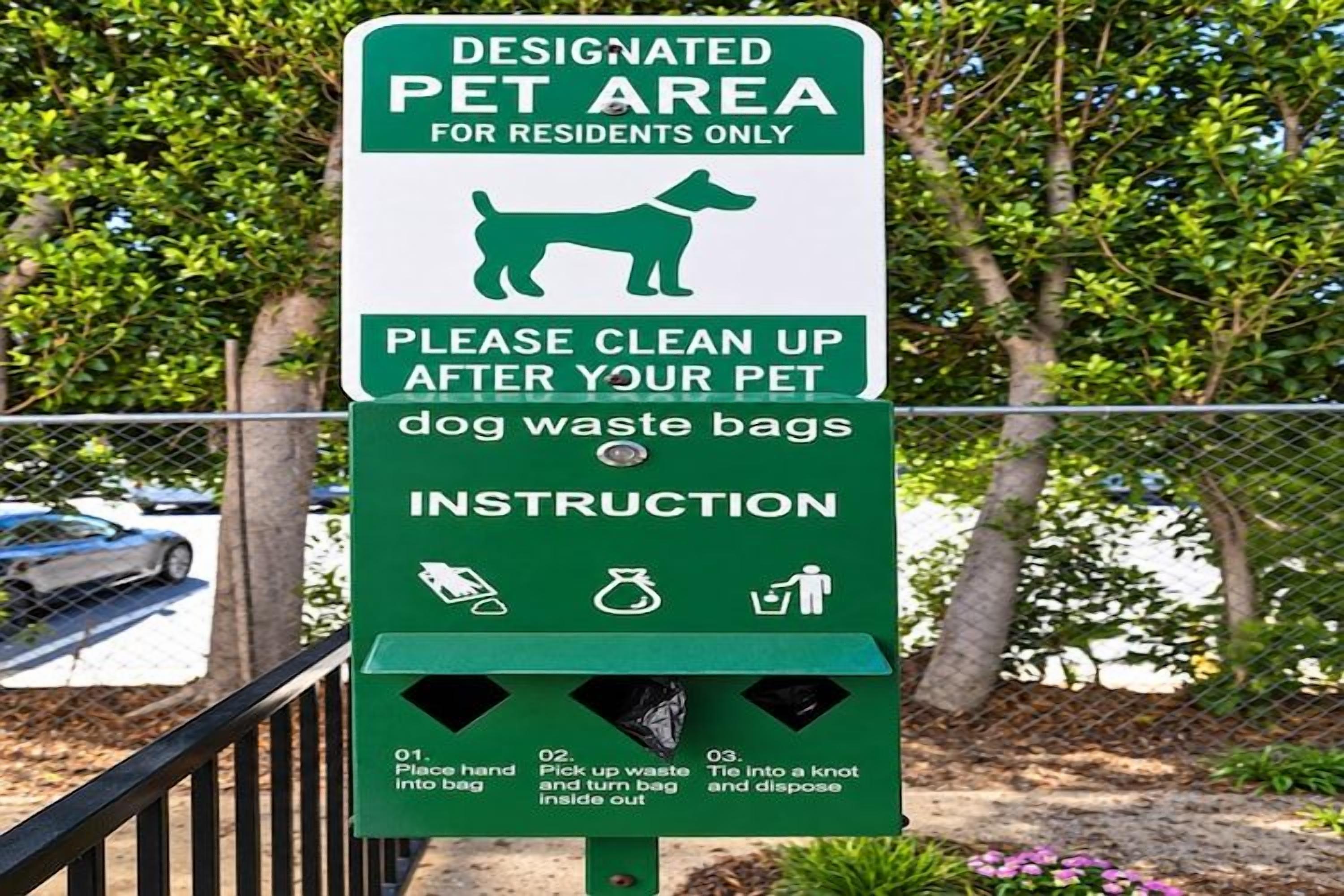 A sign with instructions for cleaning up after pets, including designated pet area and waste bag disposal.