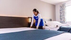 A hotel room with a bed, a nightstand, and a window with curtains. - 1 Queen Bed|Kitchen|Smoking (Greensboro)