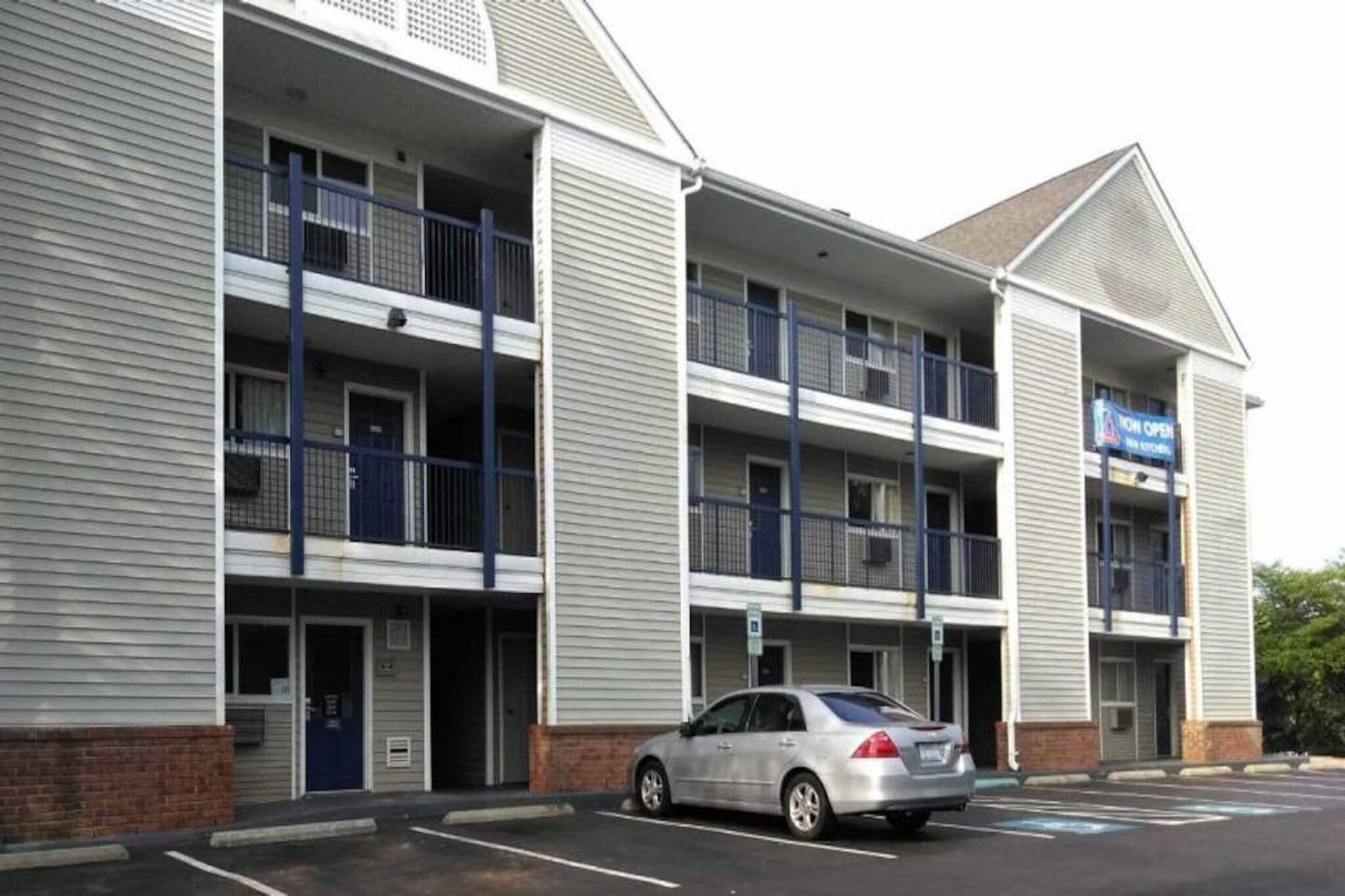 A multi-story hotel with a parking lot and a car parked in front.