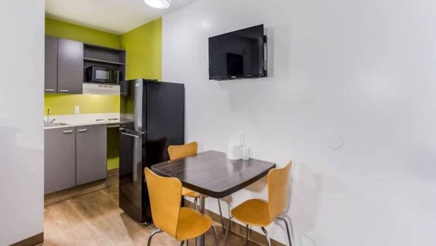 Een compacte keuken met een eethoek, inclusief een tafel en stoelen, een magnetron en een koelkast.