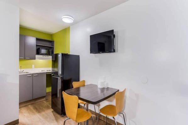 A compact kitchen with a dining area, including a table and chairs, a microwave, and a refrigerator. - Spacious 2-Bed|Free Parking & Wifi (Jacksonville)