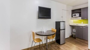Een kleine keuken met een eettafel, stoelen, een koelkast en een magnetron.