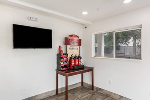 A room with a flat-screen TV mounted on the wall, a table with a coffee station, and a window with a view of trees. - Spacious 2-Bed|Free Parking & Wifi (Jacksonville)