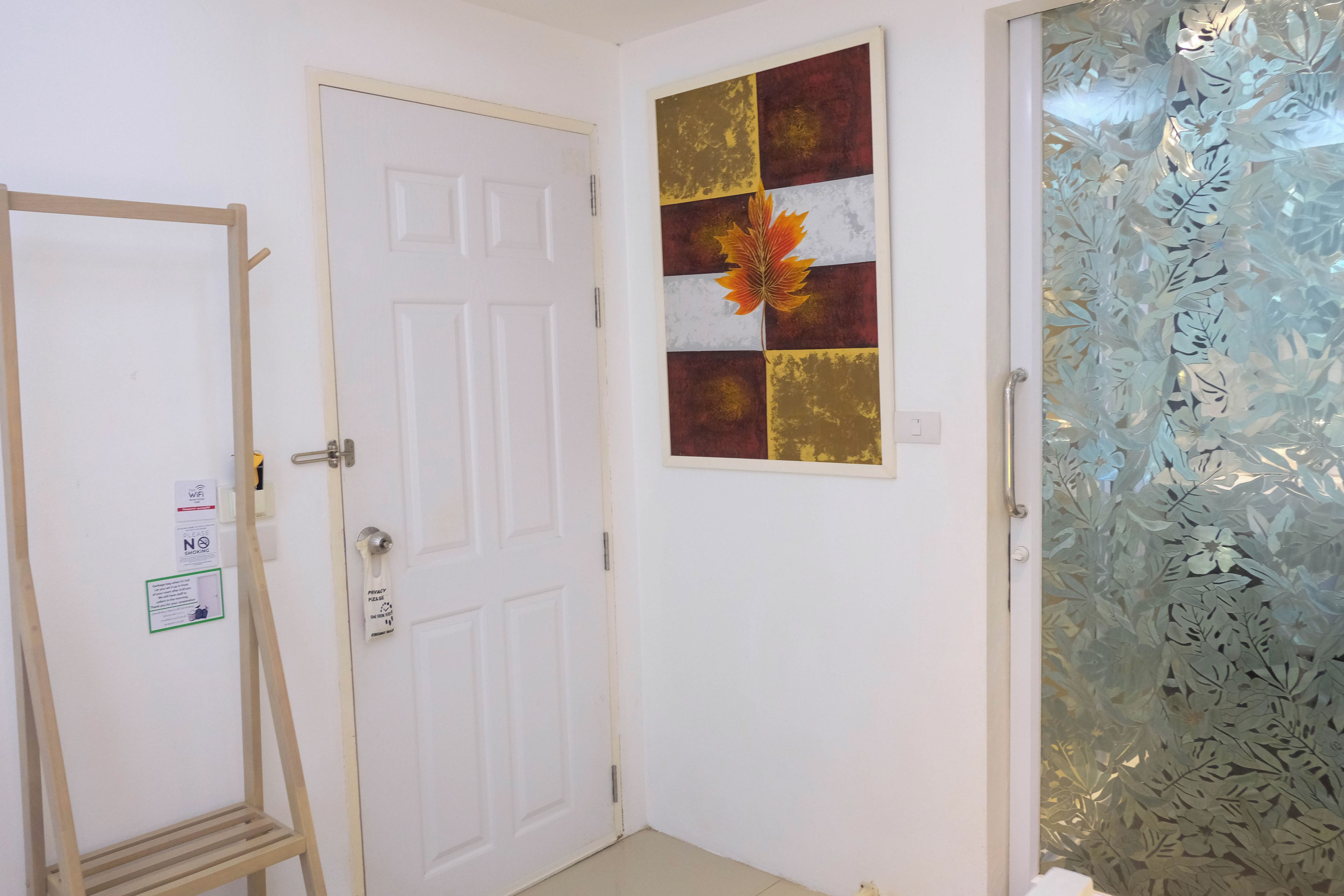 Habitación con una puerta blanca, una escalera de madera, un aviso de privacidad y una puerta de cristal con estampado floral.