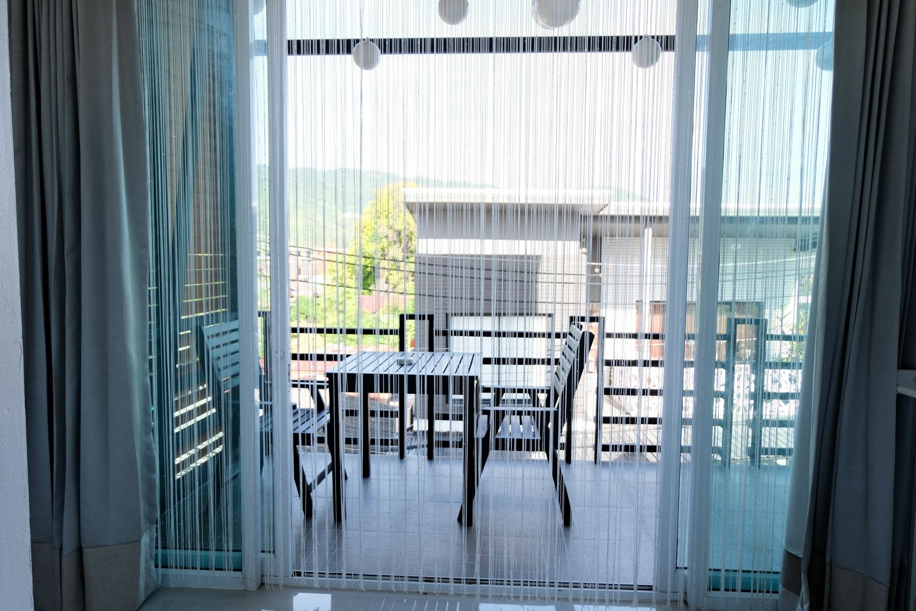 A room with a sliding glass door leading to an outdoor area with a table and chairs.