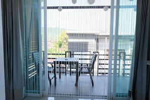 A room with a sliding glass door leading to an outdoor area with a table and chairs. - Baanpoon Apartment (Koh Samui)