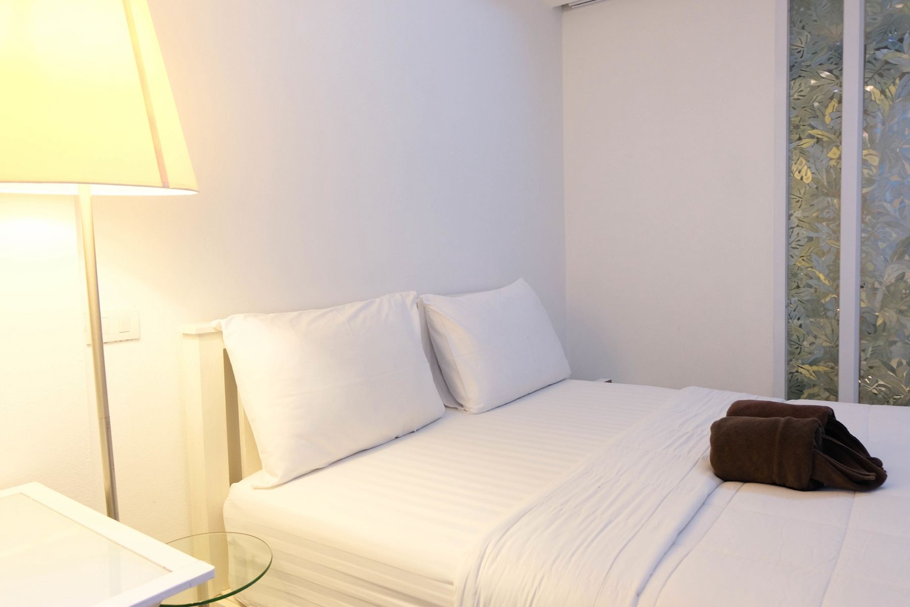 A hotel room with a bed, a bedside lamp, and a window with a view.