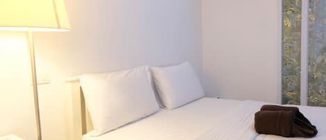A hotel room with a bed, a bedside lamp, and a window with a view.