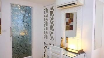 A room with a frosted glass door, a white cabinet with a mirror, and a white chair.