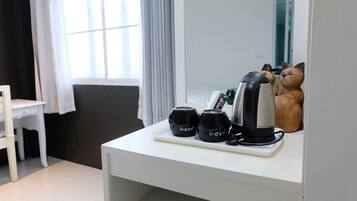 A white desk with a kettle, two black mugs, and a small plant.