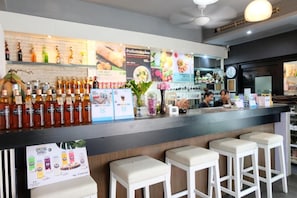A bar area with stools, a counter, and various bottles. - Baanpoon Apartment (Koh Samui)