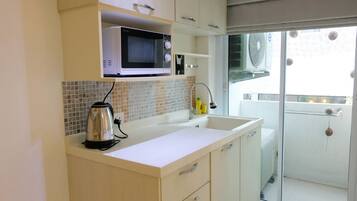 A kitchen with a microwave, kettle, and sink.