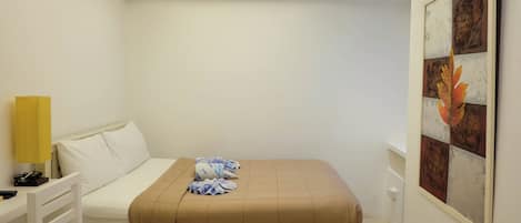 A hotel room with a bed, a bedside table with a lamp, and a wall-mounted artwork.