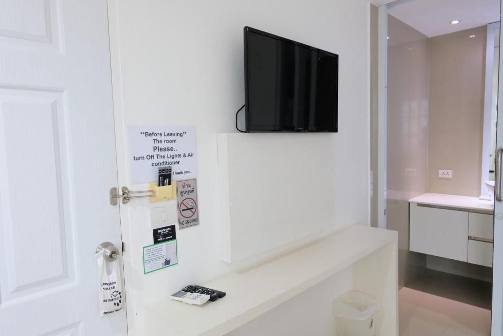 Een hotelkamer met een aan de muur bevestigde televisie, een privacyvermelding, een rookverbods-bordje en een Wi-Fi-sign.