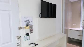 Een hotelkamer met een aan de muur bevestigde televisie, een privacyvermelding, een rookverbods-bordje en een Wi-Fi-sign.