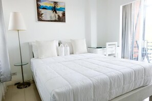 Una habitación de hotel con una cama grande, un escritorio, una silla y un cuadro en la pared.