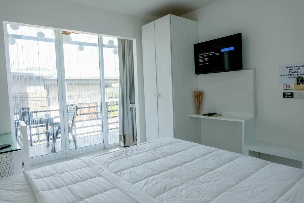 Et hotelværelse med seng, fjernsyn, balkon med udsigt og et skilt med instruktioner.