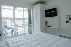 Habitació d'hotel amb un llit, una televisió, un balcó amb vistes i un cartell amb instruccions.