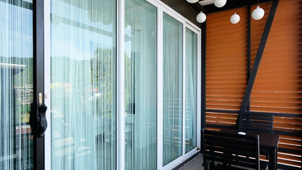 Un interior modern amb portes corredisses de vidre, una paret de lamel·les de fusta i una cadira negra.