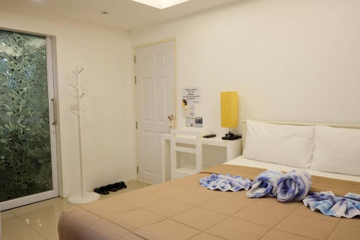 Hotellihuone, jossa on sänky, työpöytä, tuoli, lamppu ja ovi.