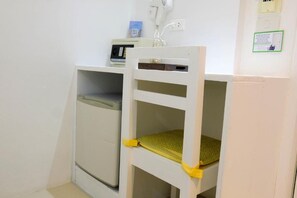Un espacio pequeño y cerrado con una silla y un mueble blancos.
