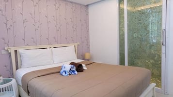 Un dormitorio con cama, mesita de noche, lámpara y vistas a través de un ventanal.