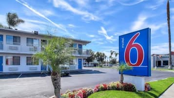 A motel with a large blue sign, a parking lot, and a building with balconies.