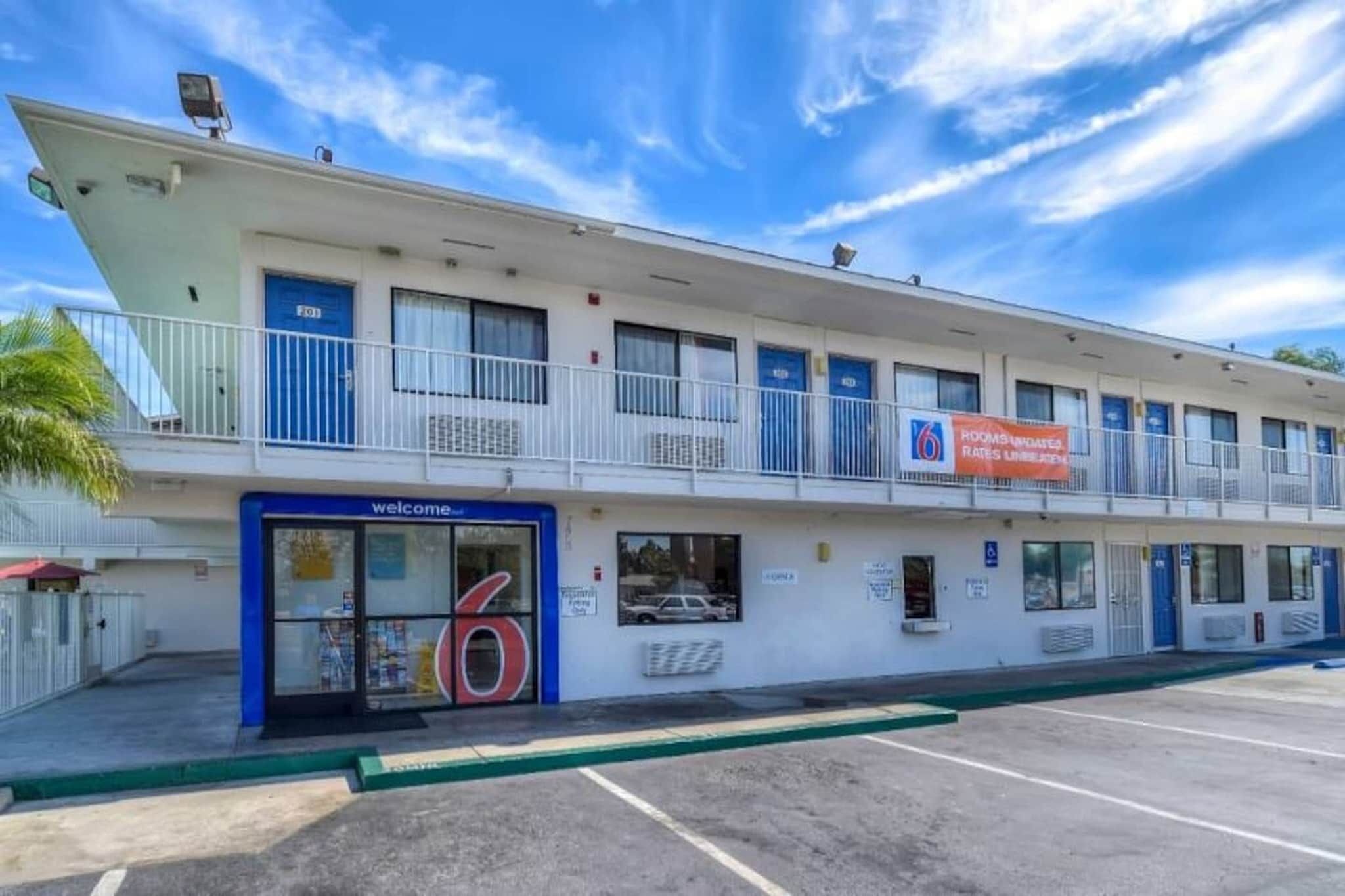 A motel with a '6' sign, a 'Welcome' sign, and a banner advertising room rates.
