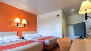 Habitación de hotel con dos camas, un escritorio, un televisor y dos lámparas de pared.