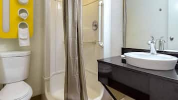 A bathroom with a white toilet, a shower with a glass door, a sink with a mirror, and a towel rack with towels.