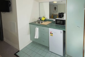 A compact kitchenette with a sink, a microwave, a small refrigerator, and a mirror above the counter. - Peaceful 1BD Studio with Balcony, Chermside (Chermside)