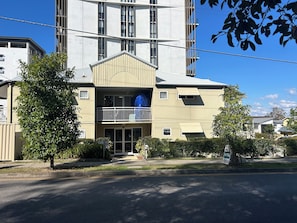 A multi-story building with a central entrance, a covered balcony, and a visible sign indicating a hotel. - Peaceful 1BD Studio with Balcony, Chermside (Chermside)