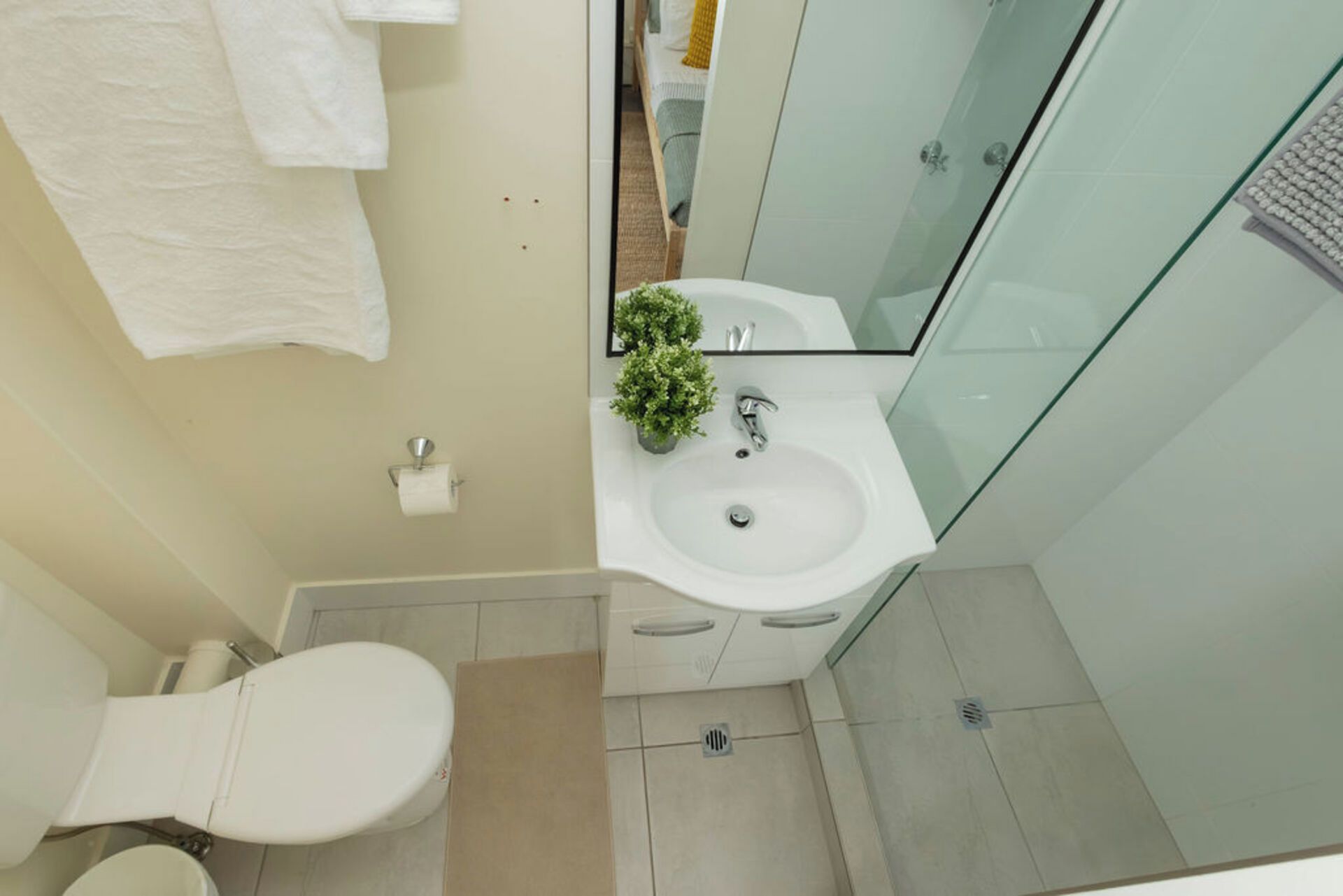 Et lille badeværelse med toilet, håndvask og spejl.