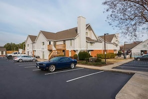 A multi-story residential building with a parking lot in front. - 1 Queen Bed | ADA/RI Shower/Non-Smoking (Greensboro)