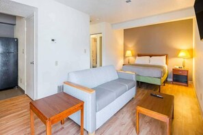 Une chambre d’hôtel avec un canapé, un lit, une table de chevet et une petite table.