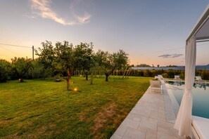 Ein Garten mit Pool, Bäumen und einem Rasen.