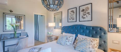 Quarto com cama grande, penteadeira, espelho e luminária pendente.