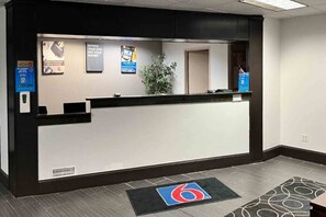 Ein Empfangsschalter mit Schwarz-Weiß-Design, eine Pflanze und ein Logo auf dem Boden.