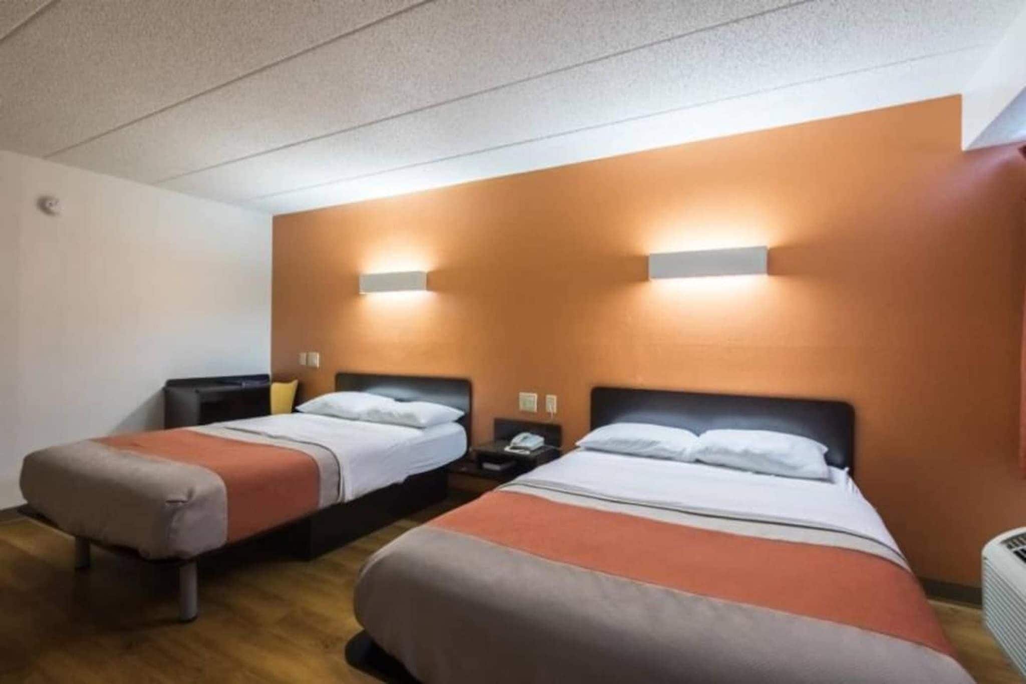 Una habitación de hotel con dos camas, cada una con una mesita de noche, una lámpara y un teléfono.