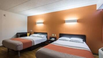 Una habitación de hotel con dos camas, cada una con una mesita de noche, una lámpara y un teléfono.