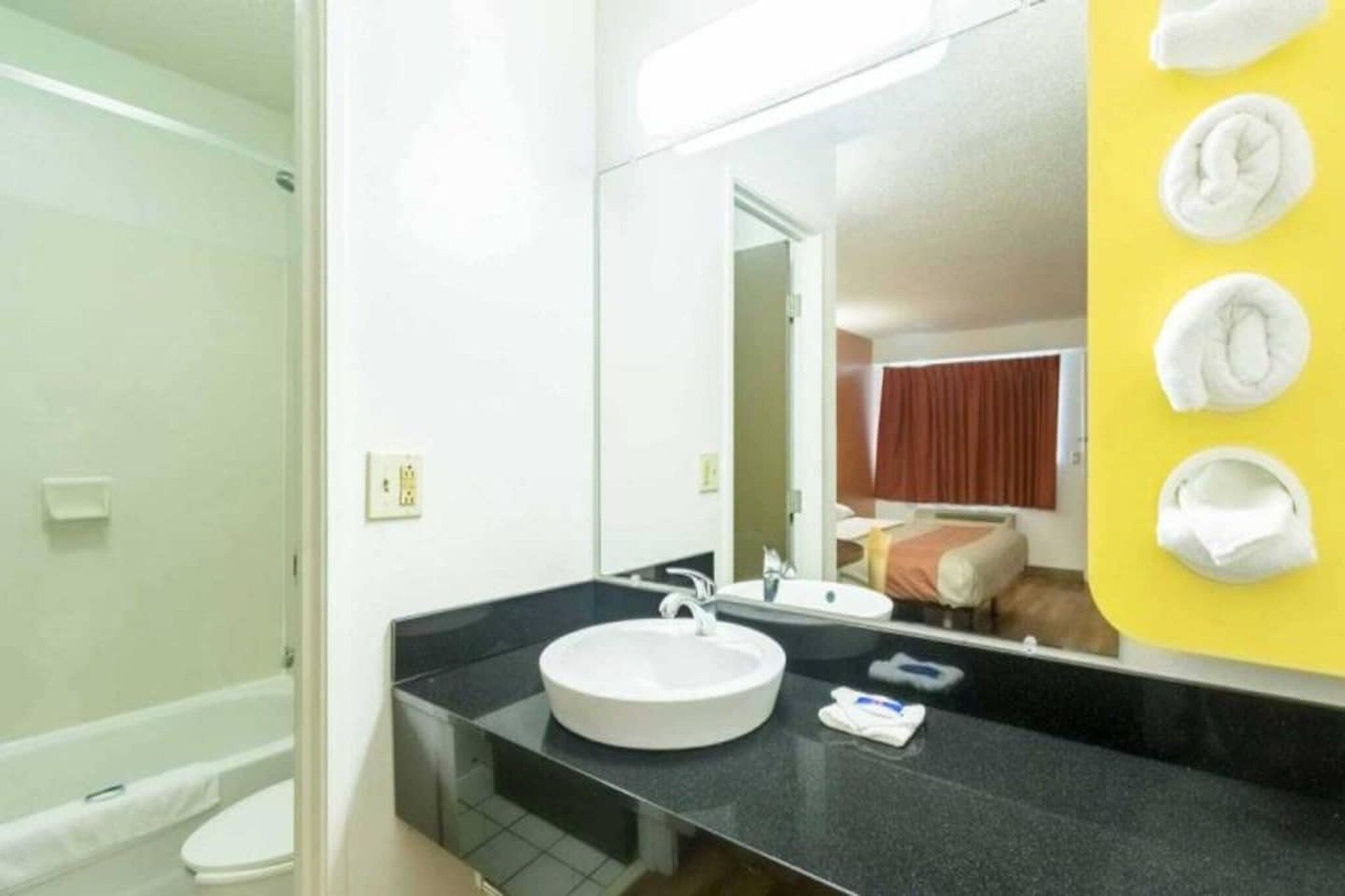 A bathroom with a round sink, a mirror, and a yellow towel rack.