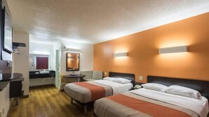 Habitación de hotel con dos camas, un escritorio, un espejo y un baño a la vista.