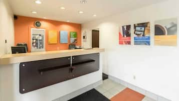 A reception desk with a computer, a clock, and informational posters on the wall.
