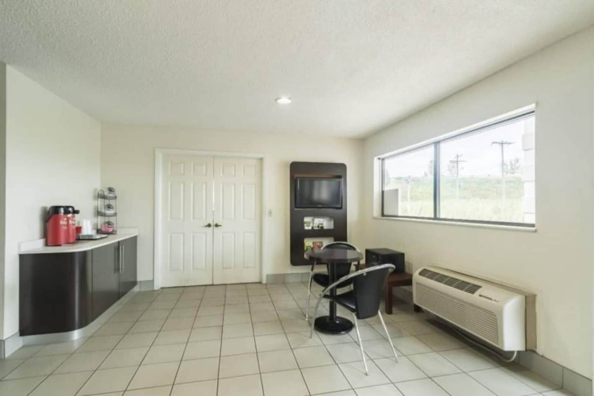 A room with a kitchenette, a dining area, and a large window.